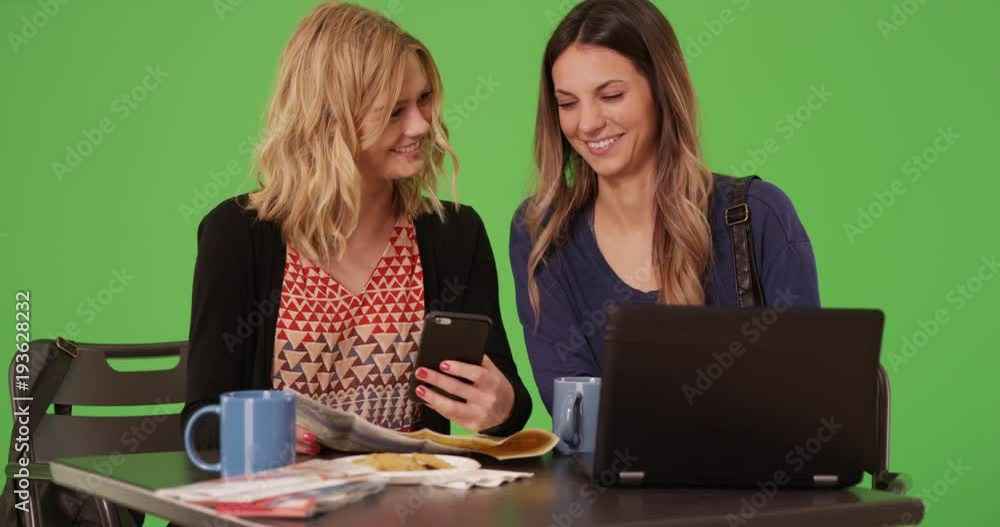 Two women traveling with maps and using smartphone to get around on greenscreen Two women traveling with maps and using smartphone to get around on greenscreen