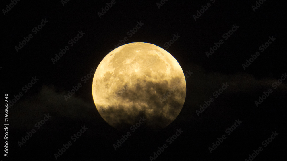 A bright full-moon behind a thin cloud.
