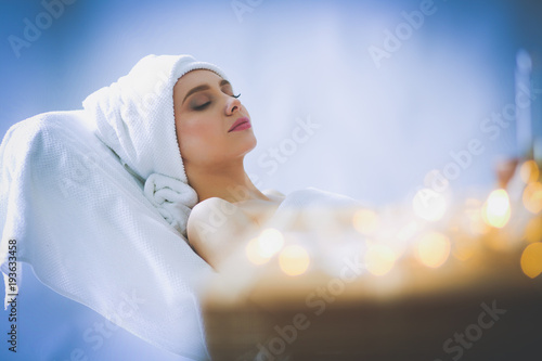 Young woman lying on a massage table,relaxing with eyes closed. Woman. Spa salon photo