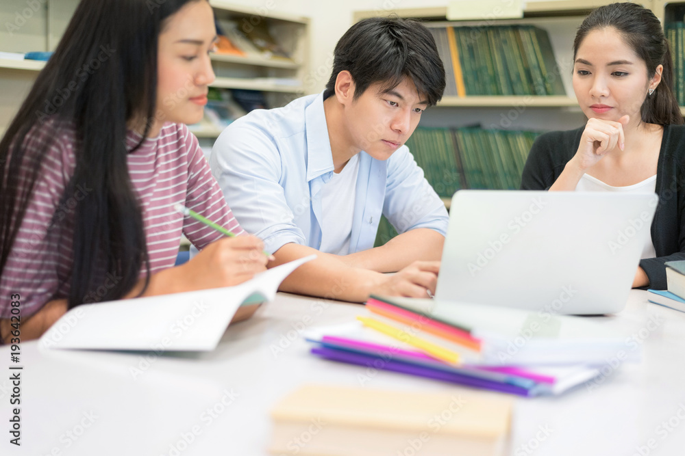 Group of Happy young people using labtop computer working homework together in Library. Students is Brainstorming for homework. Setup studio shooting. Group of Happy young people using labtop computer working homework together in Library. Students is Brainstorming for homework. Setup studio shooting.