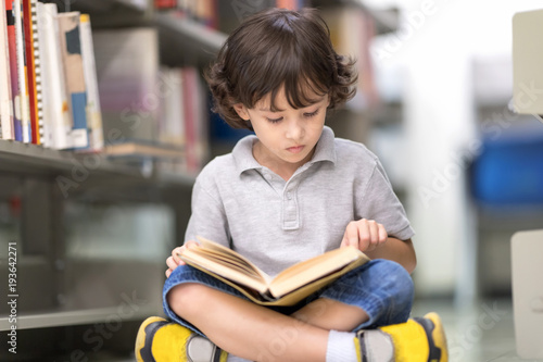 Smart boy with many books sitting on floor .Happy Children Learning Class in Library. Development of Human Resources in Education Concept. Setup studio shooting.