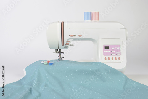 Sewing machine and colorful thread rolls, scissors, fabric and accessories for sewing on white background, Sewing and needlework concept. (Selective Focus)