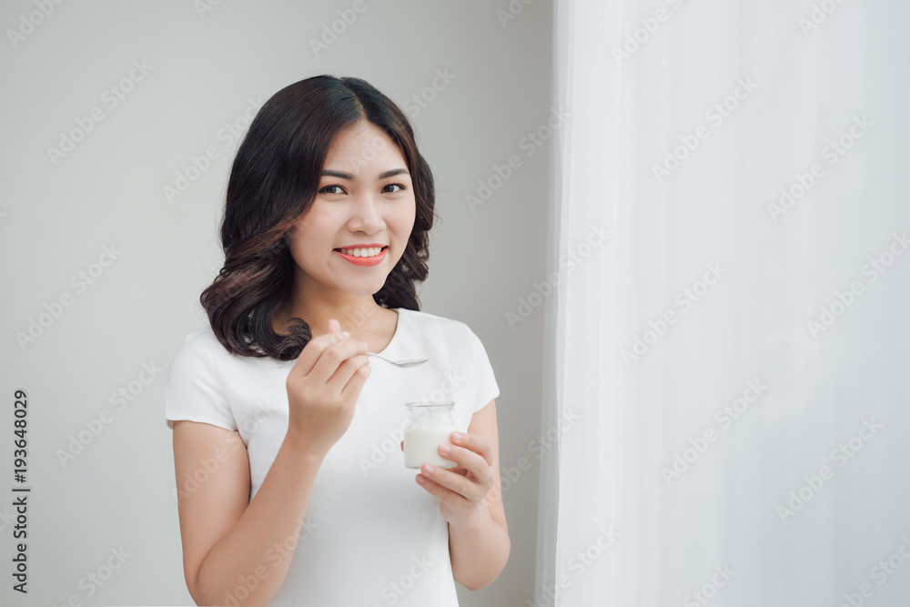 Portrait of young asian woman at home eating yogurt Portrait of young asian woman at home eating yogurt