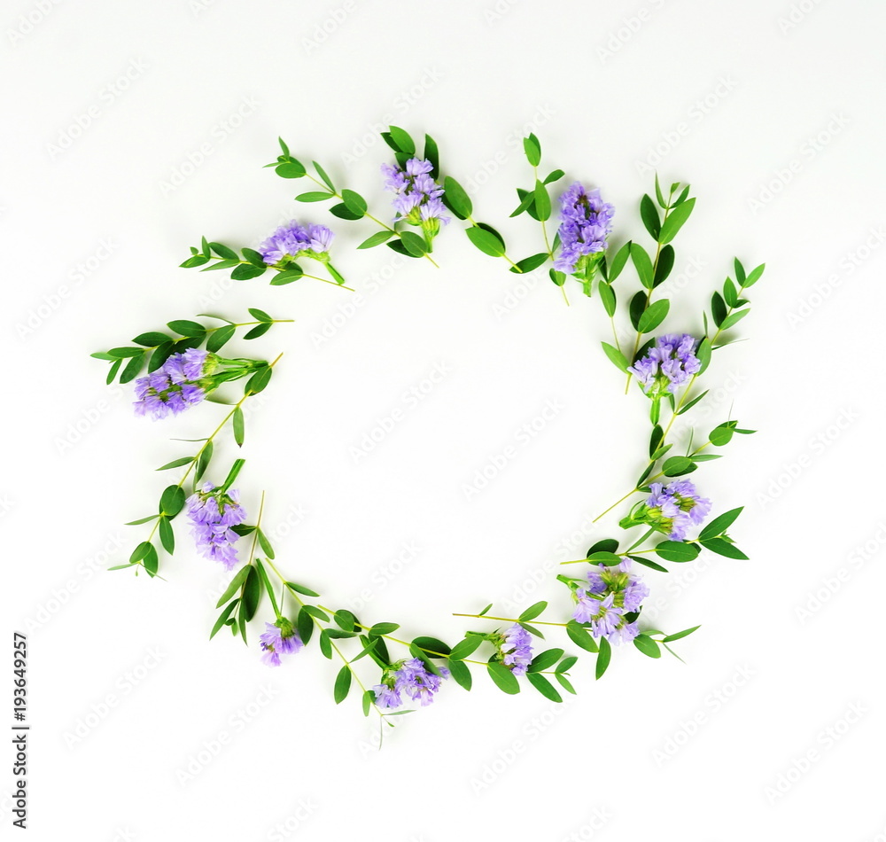 Flowers background. Wreath made of branches of eucalyptus and purple flowers on a white background. Flat lay. top view. copy space Flowers background. Wreath made of branches of eucalyptus and purple flowers on a white background. Flat lay. top view. copy space
