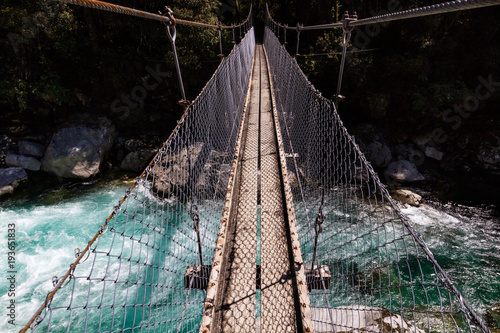 Suspension bridge over a beautiful turquoise river on the Hollyford Road, Fiordland National Park, New Zealand photo