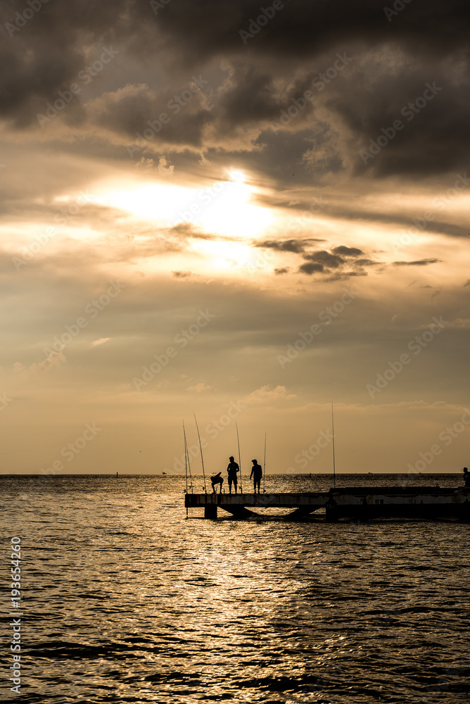 Fisherman silhouette with sunset sky at the sea
