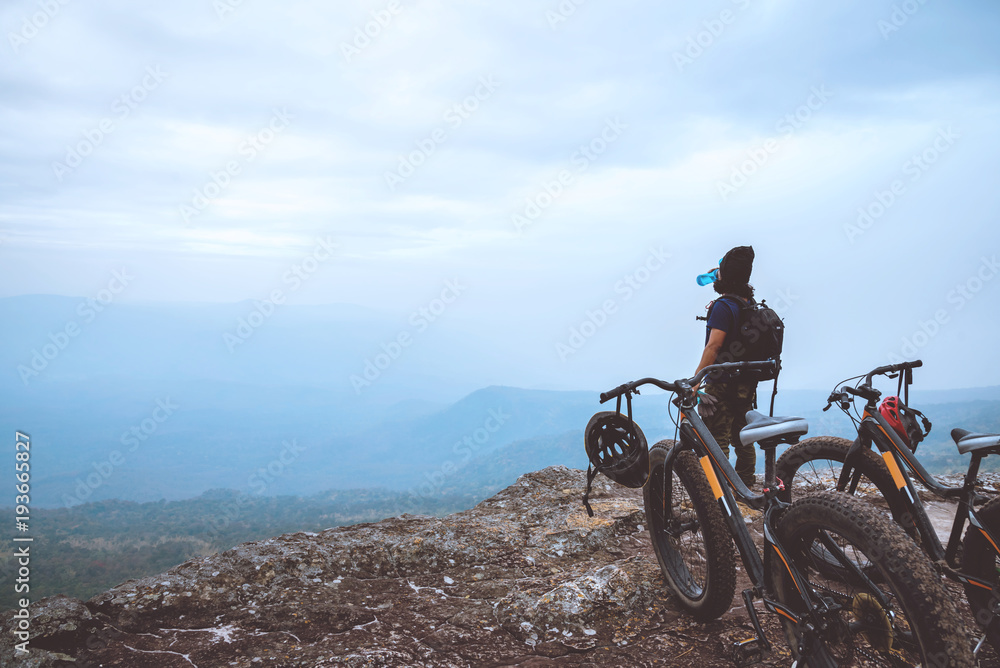 Asian men travel nature. Travel relax ride a bike Wilderness in the wild.Stand on the line. In the meadow in the woods. Thailand