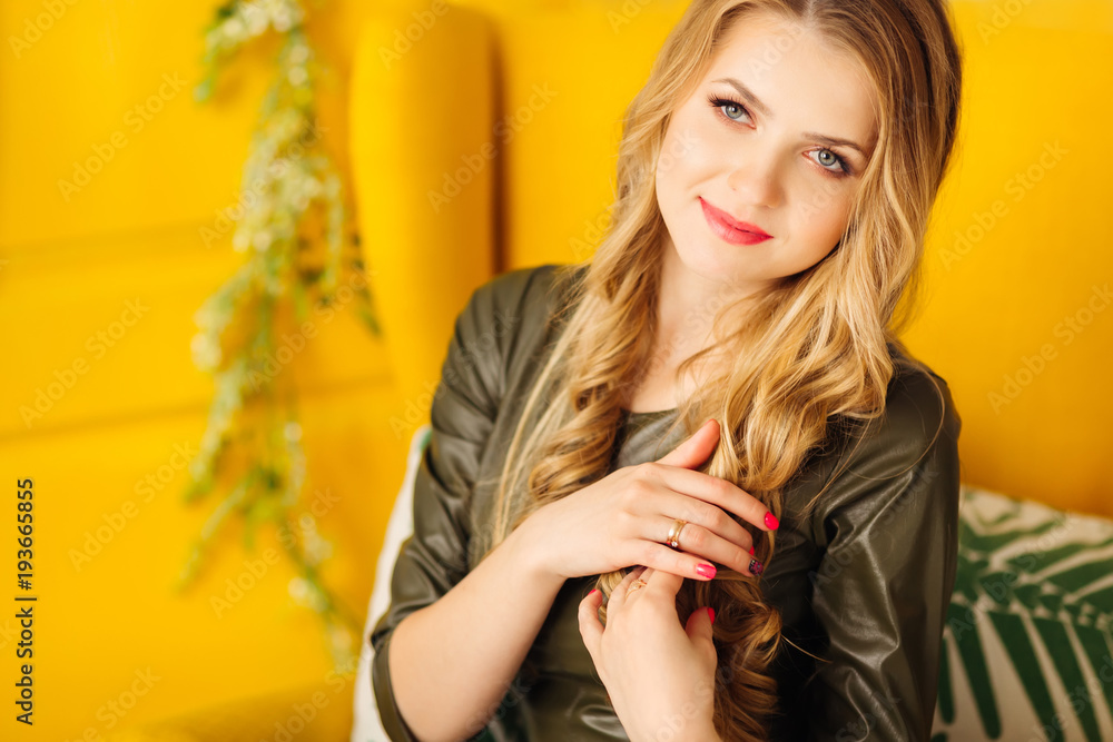 close-up of a beautiful woman with a wonderful hairdo and a gentle make-up who sits in a yellow armchair close-up of a beautiful woman with a wonderful hairdo and a gentle make-up who sits in a yellow armchair
