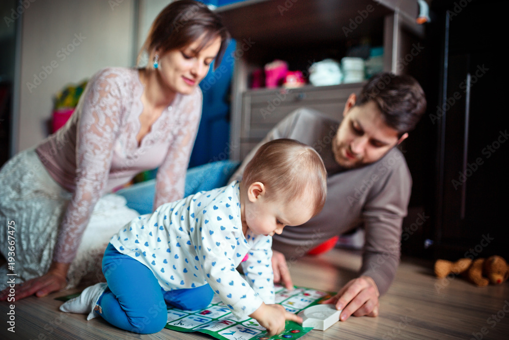 young parents play with their little daughter on the floor. Many toys.  happy family concept