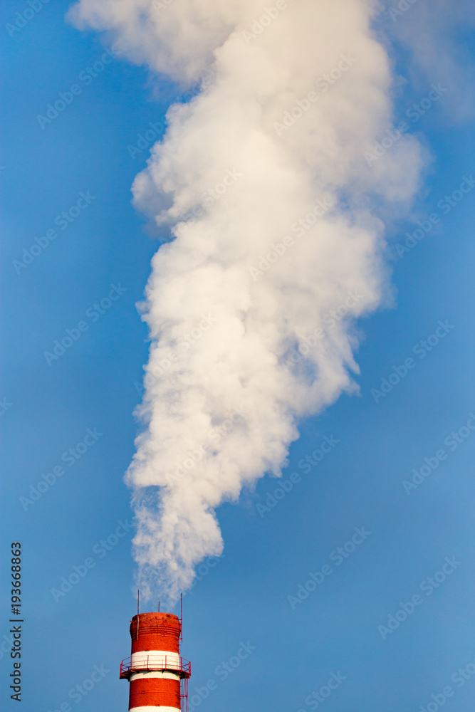 smoke from a pipe in the factory against a blue sky