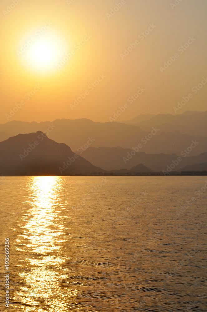 sunset on the coast of the Gulf of Oman against the background of mountain ranges