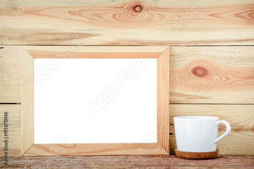 Wooden frame isolated with decorations from a white cup on a wooden background.