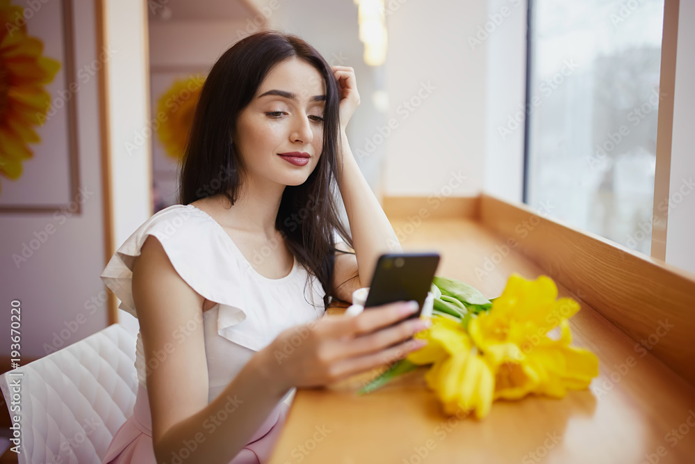 Girl sitting at the cafe and drinking coffee, taking selfies and enjoying flowers gifted by her boyfriend Girl sitting at the cafe and drinking coffee, taking selfies and enjoying flowers gifted by her boyfriend