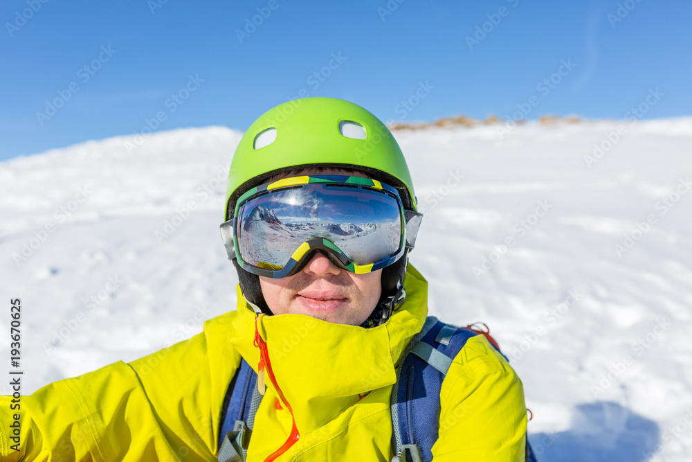 Photo of sporty man wearing mask and helmet against background of snowy mountain landscape