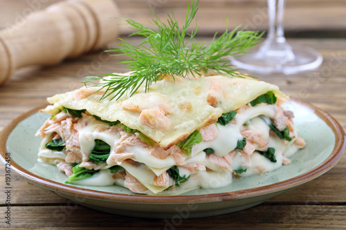 lasagne al forno con salmone e spinaci su sfondo rustico