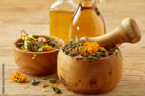 Beautiful composition of glass oil jars, wooden mortar and pestle with flax seeds, shallow depth of field photo