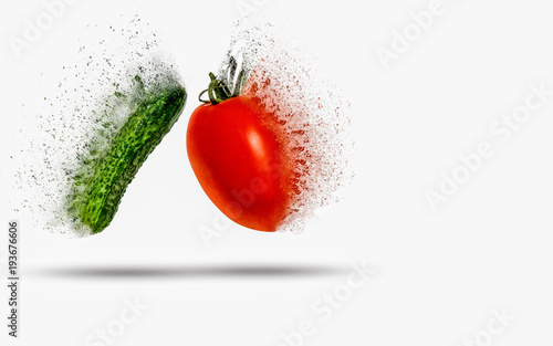 Tomato and cucumber exploding (dispersing) on white background photo