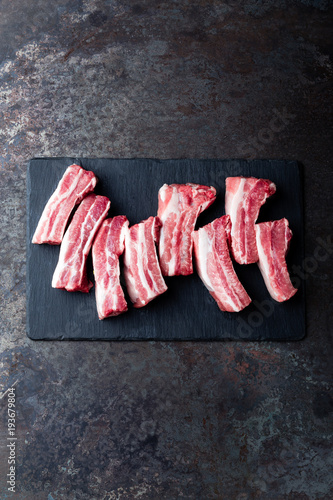 Raw uncooked pork ribs, fresh meat on dark metal background. Top view. Flat lay.