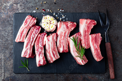 Raw uncooked pork ribs, fresh meat on dark metal background. Top view. Flat lay.