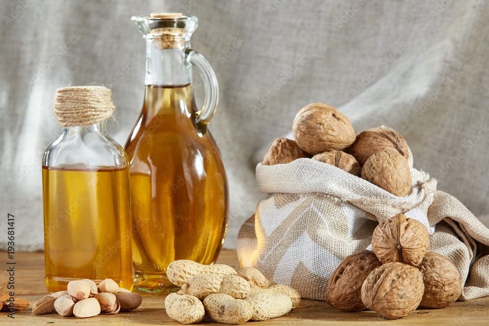 Conceptual composition of glass oil jars with different kinds of nuts on wooden table, close-up. Conceptual composition of glass oil jars with different kinds of nuts on wooden table, close-up.