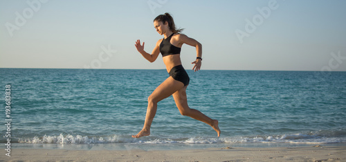 Panoramic view of sporty girl running on the beach.