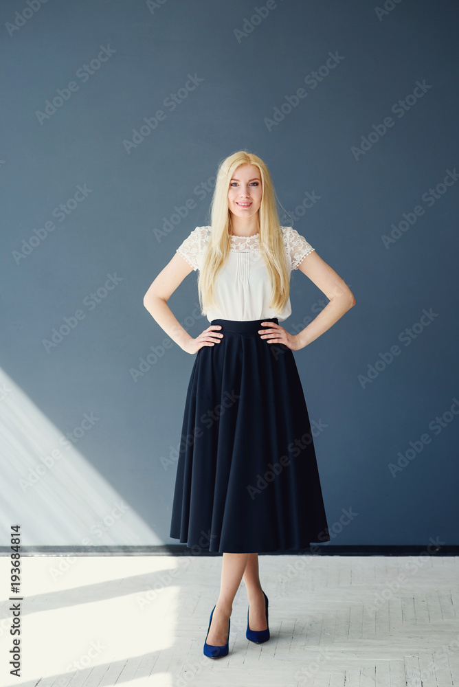 Full length portrait of a beautiful blonde girl in black white clothes on the grey blue studio background Full length portrait of a beautiful blonde girl in black white clothes on the grey blue studio background
