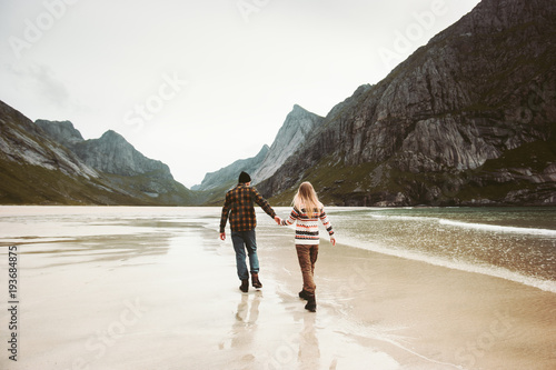 Romantic Couple in love walking holding hands on sea beach in Norway man and woman together traveling Lifestyle concept vacations outdoor photo