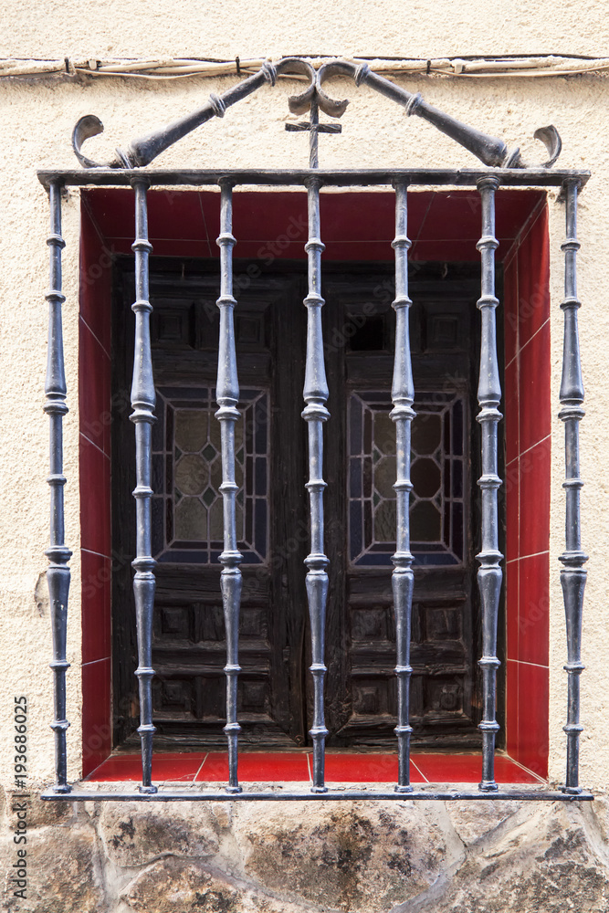 ventana antigua con cristales de colores y madera y protegida por barrotes  de hierro forjado con formas redondeadas en una pared mitad de piedra mitad  pintada foto de Stock | Adobe Stock