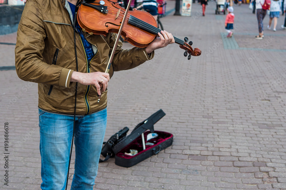 Street violinist plays the violin at noon, autumn day