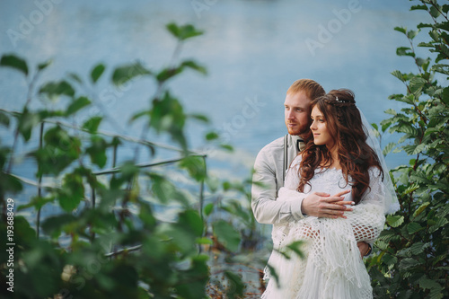 stylish bride and groom posing on the background of the river photo