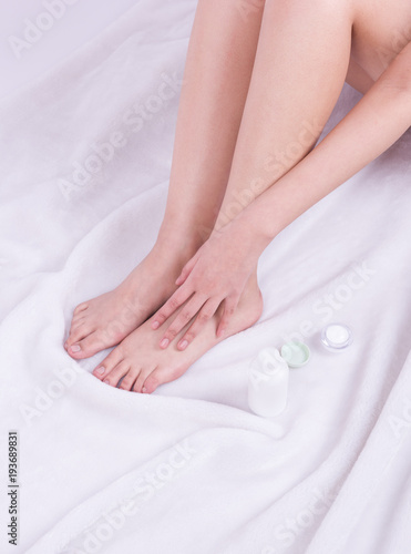 Body care. Woman hand on female feet, and body cream.