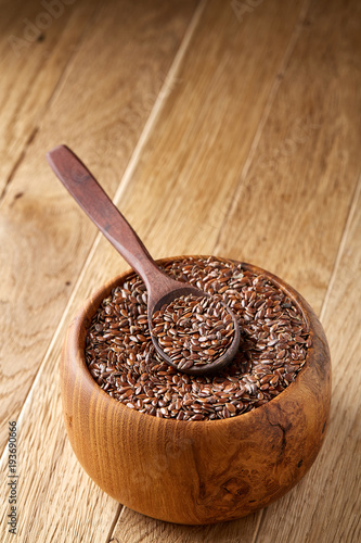 Flax seeds in wooden bowl and spoon on rustic wooden background, top view, shallow depth of field