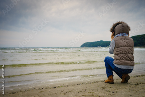 Woman walking on beach, autumn cold day © Voyagerix