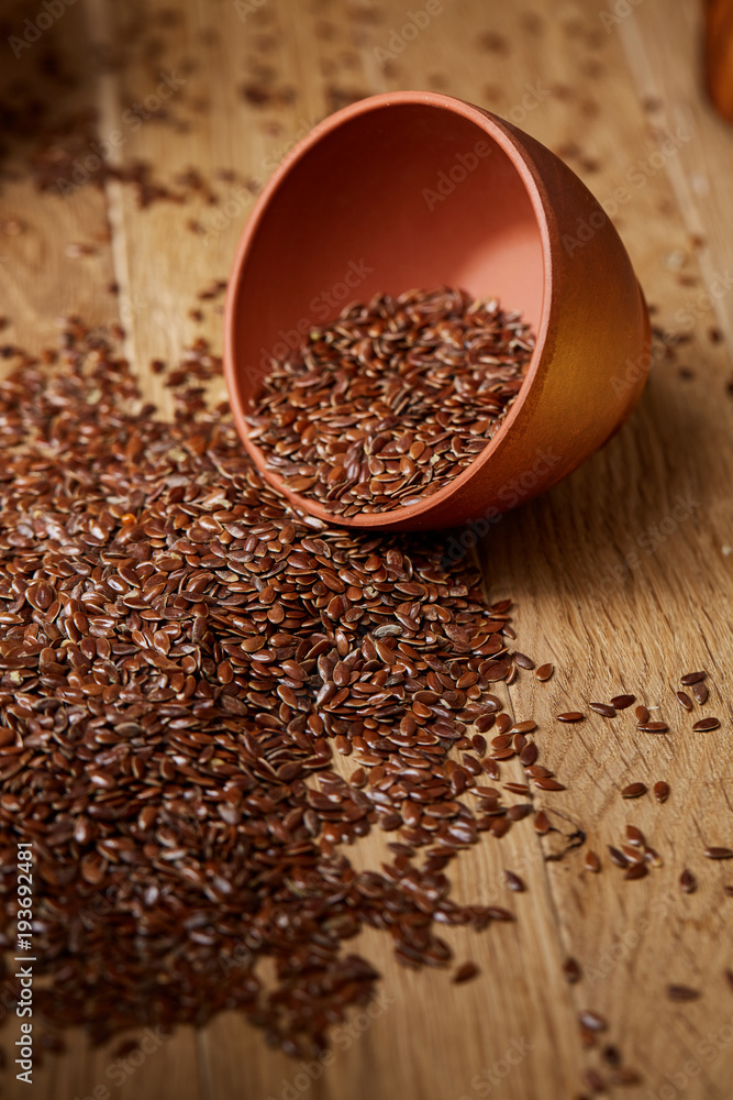 An overturned ceramic bowl with linseeds on a rustic background, close-up, shallow depth of field, selective focus