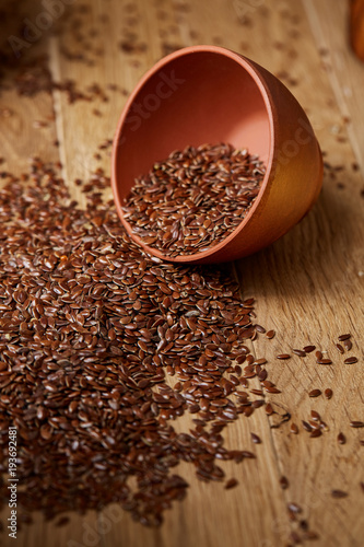 An overturned ceramic bowl with linseeds on a rustic background, close-up, shallow depth of field, selective focus