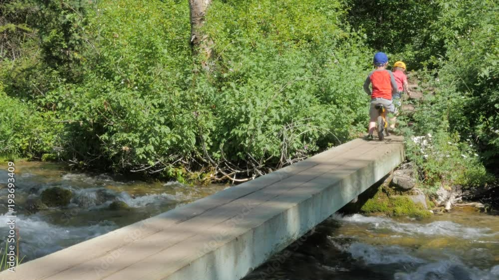 Two boys playing on and crossing a bridge over a river. Two boys playing on and crossing a bridge over a river.