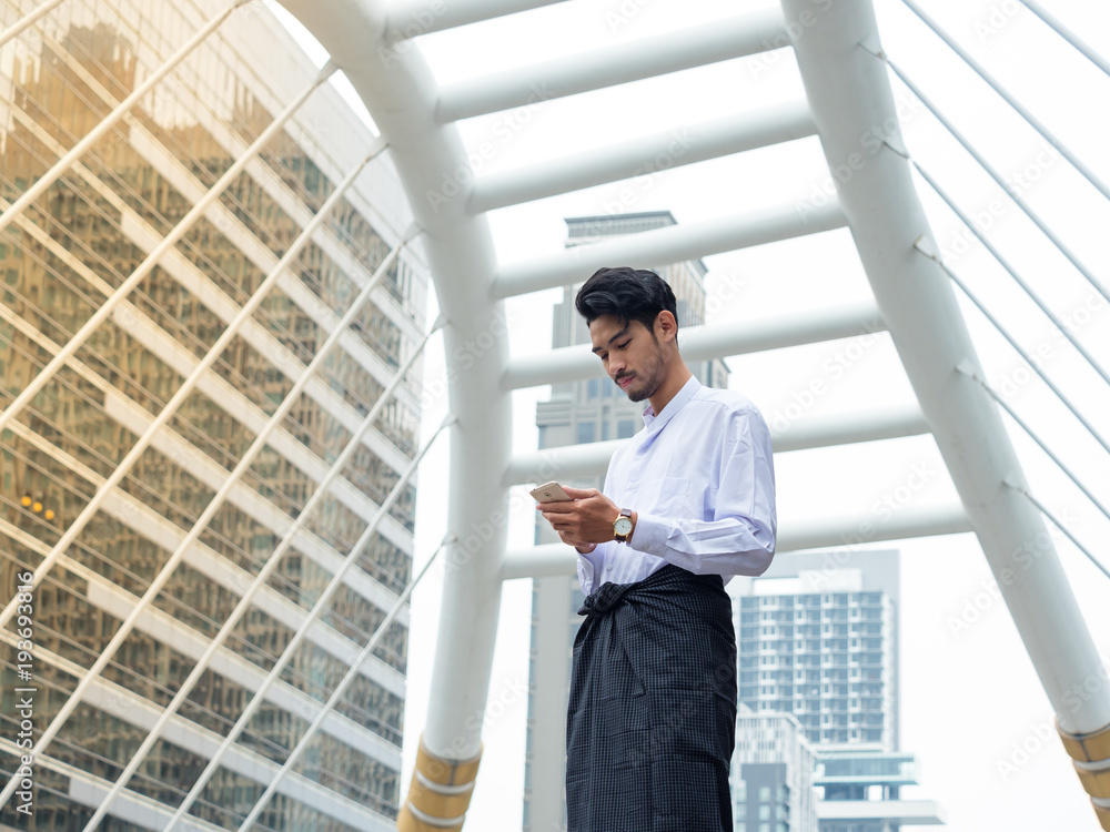 Young Burmese businessman using mobile phone to find a data for his business Young Burmese businessman using mobile phone to find a data for his business