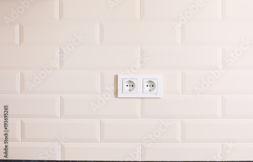 electric socket on a white tiled wall © serikbaib