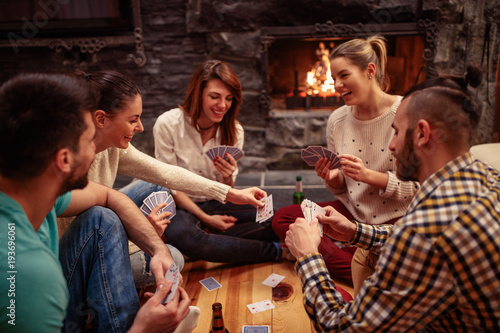 Smiling friends partying together and playing cards