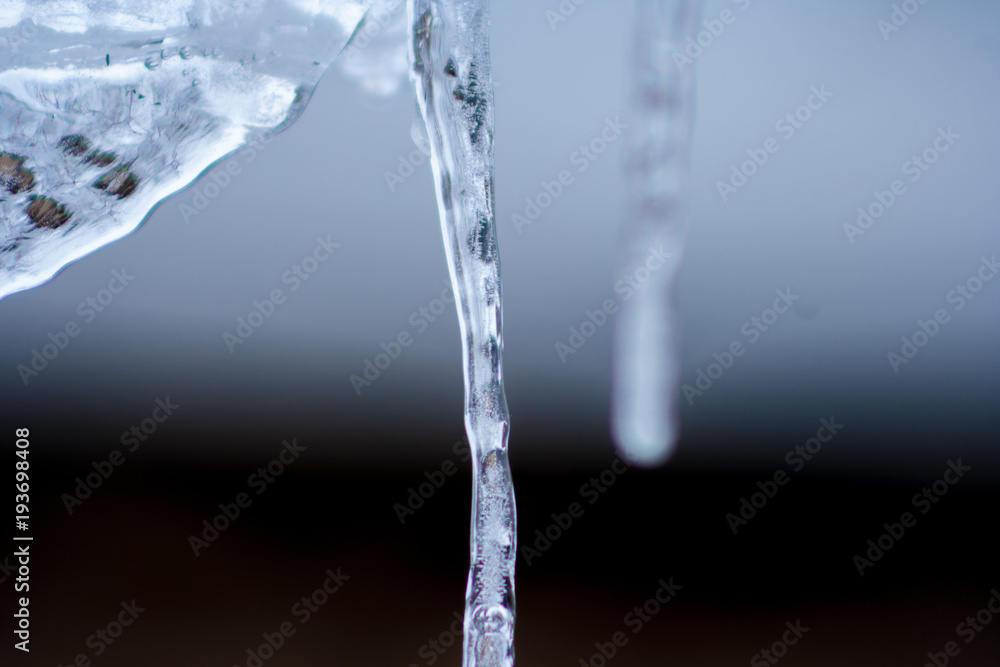 Close up of shiny and blue icicles with a dark background Close up of shiny and blue icicles with a dark background