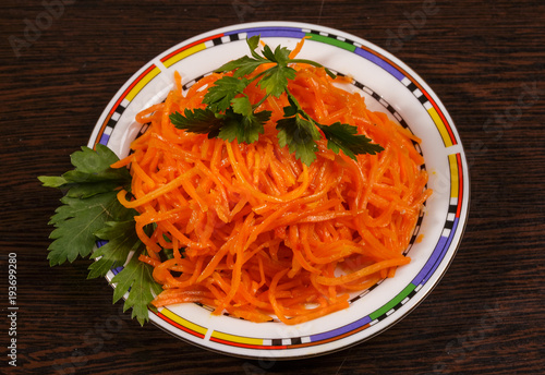 Carrots finely chopped and parsley on a plate on the table.