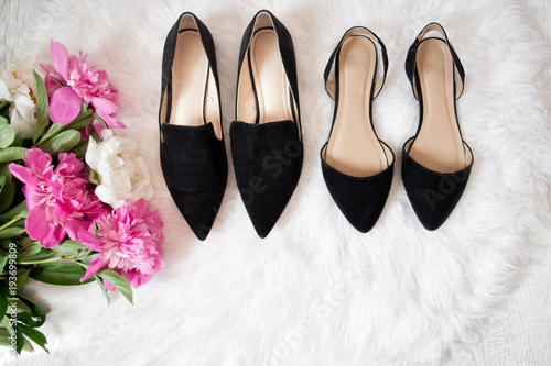 Black shoes on white fur. Bouquet of peonies. Fashionable concept