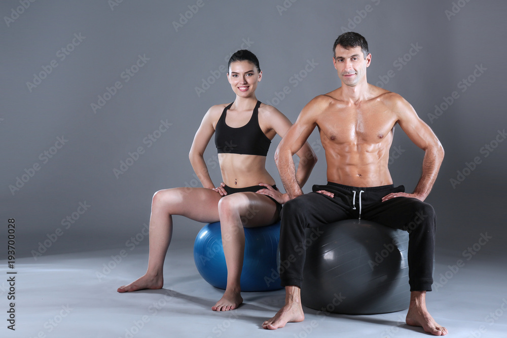 Two smiling people with fitness ball in the gym. Personal fitness instructor. Personal training. Gym workout. Two smiling people with fitness ball in the gym. Personal fitness instructor. Personal training. Gym workout.