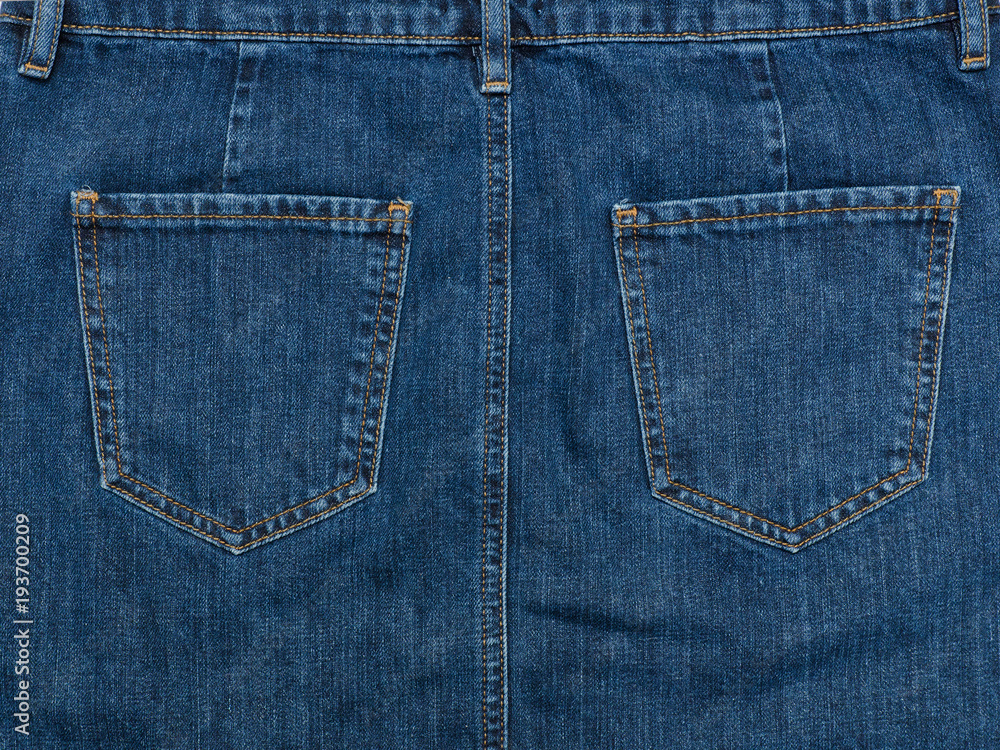 Part of the blue denim skirt. Wooden background, fashionable concept Part of the blue denim skirt. Wooden background, fashionable concept