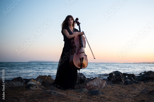Young beautiful girl with her cello on the outside