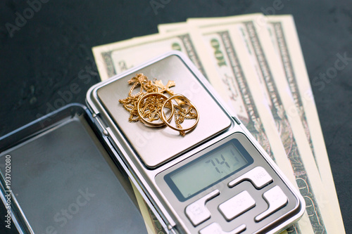 Gold jewelry on the scales and money on a black background