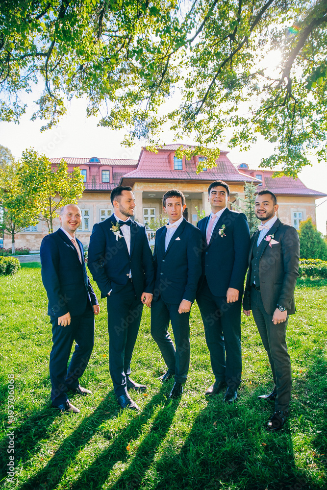 Wedding funny day. Groomsmen throw groom up standing in the park.