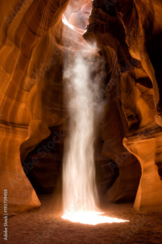 A photo of one of the spectacular light beams in Upper Antelope Canyon located in Page  Arizona. A long exposure of sand falling through the beam gives it an unusual waterfall look through the light.