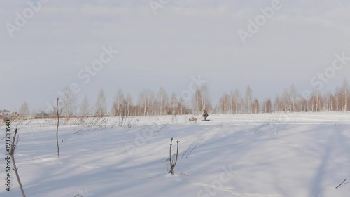 Man in winter clothes riding on mini snowmobile on deep snowdrifts photo