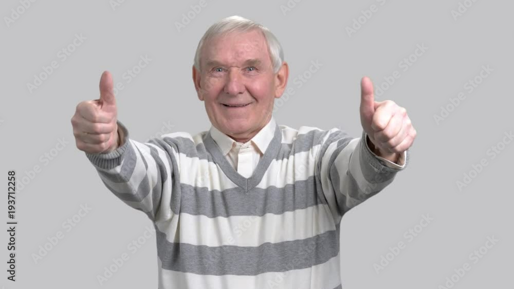Happy grandfather with two thumbs up. Cheerful eldery man giving thumbs up sign on grey background. Gesture of success and happiness. Happy grandfather with two thumbs up. Cheerful eldery man giving thumbs up sign on grey background. Gesture of success and happiness.